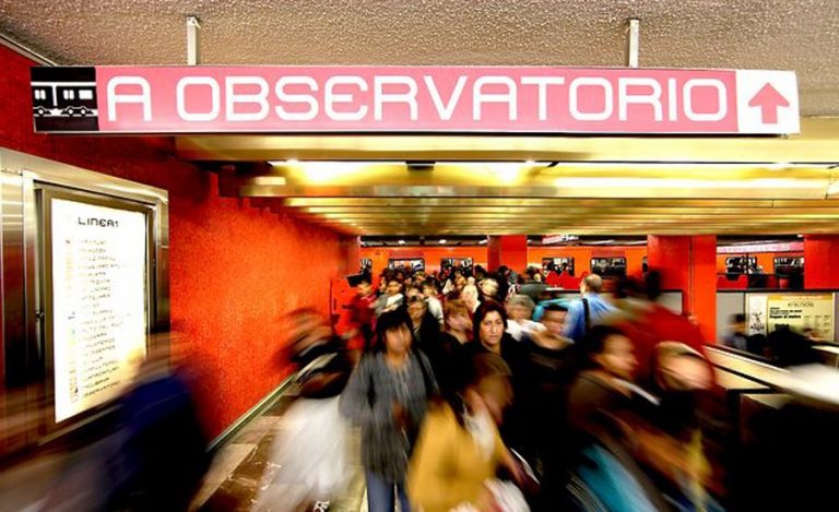 Estacion de la linea 2 del metro de color rosa, donde se nota a pasajeros caminando direccion hacia a ti con leve desvanecimiento 
        